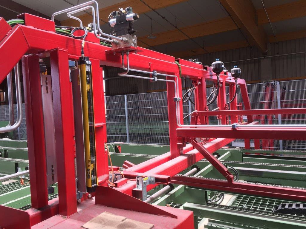 Červené automatizované výrobní zařízení s hydraulickými systémy a bezpečnostními bariérami